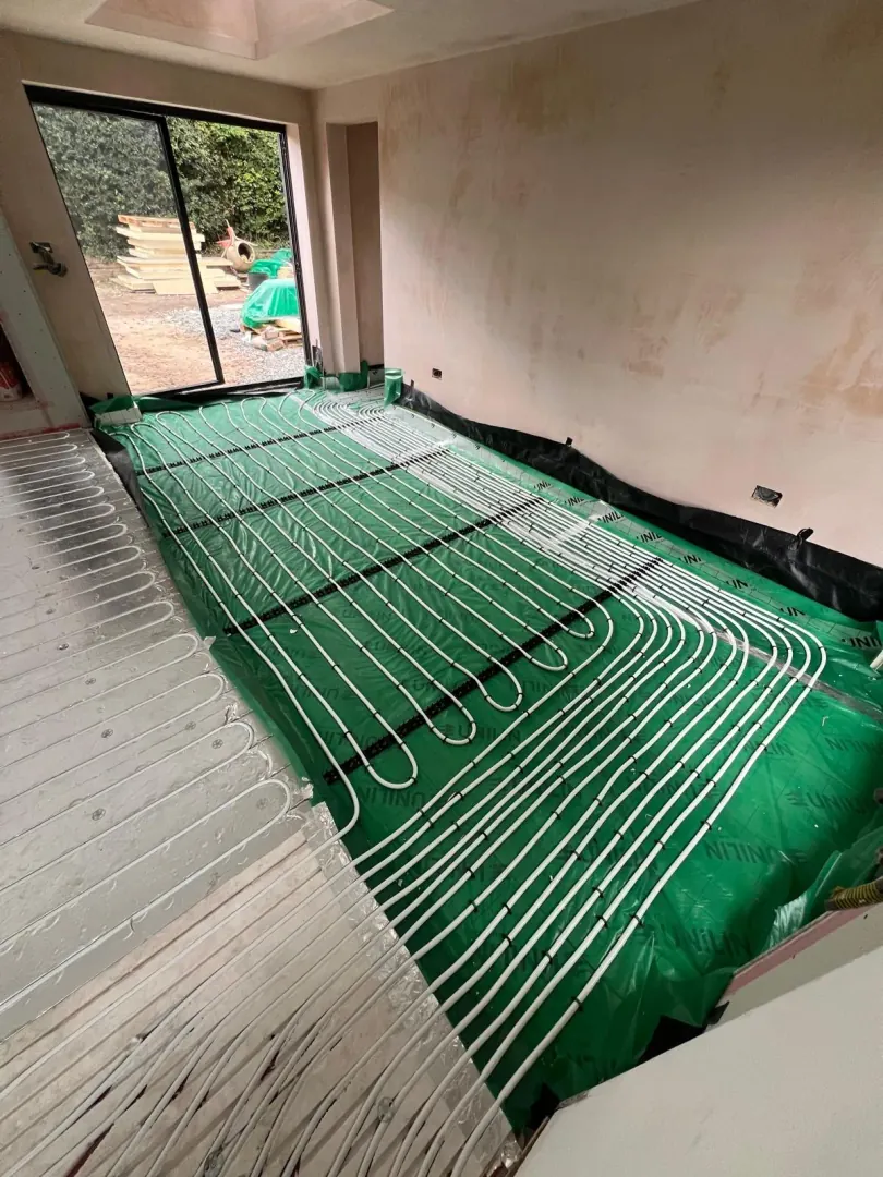 Underfloor heating pipe runs laid across multiple rooms before screed